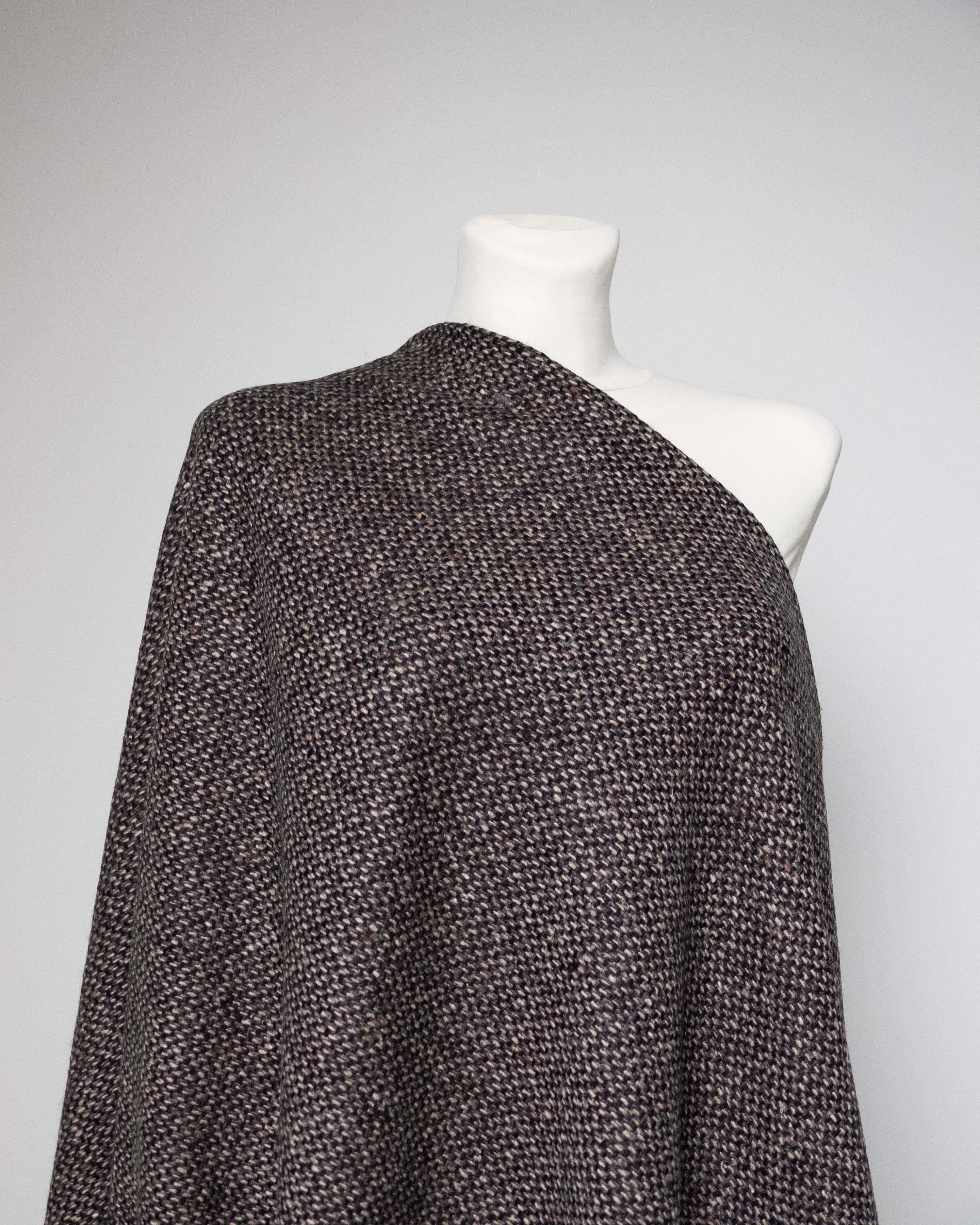 A dark brown and black textured knit shawl draped over a white mannequin torso, shown against a neutral light gray background.