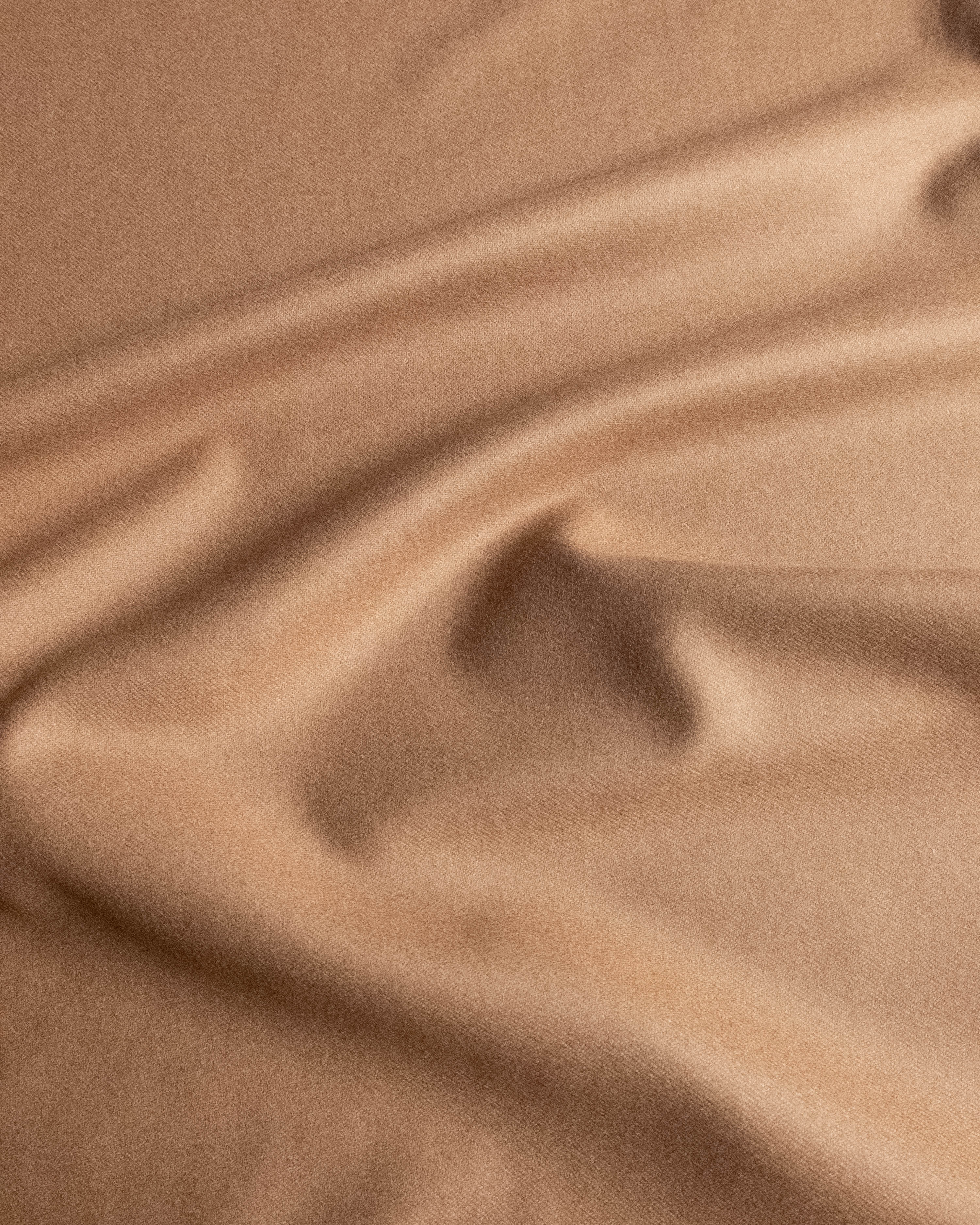 A close-up of draped beige fabric with soft folds and a smooth texture.