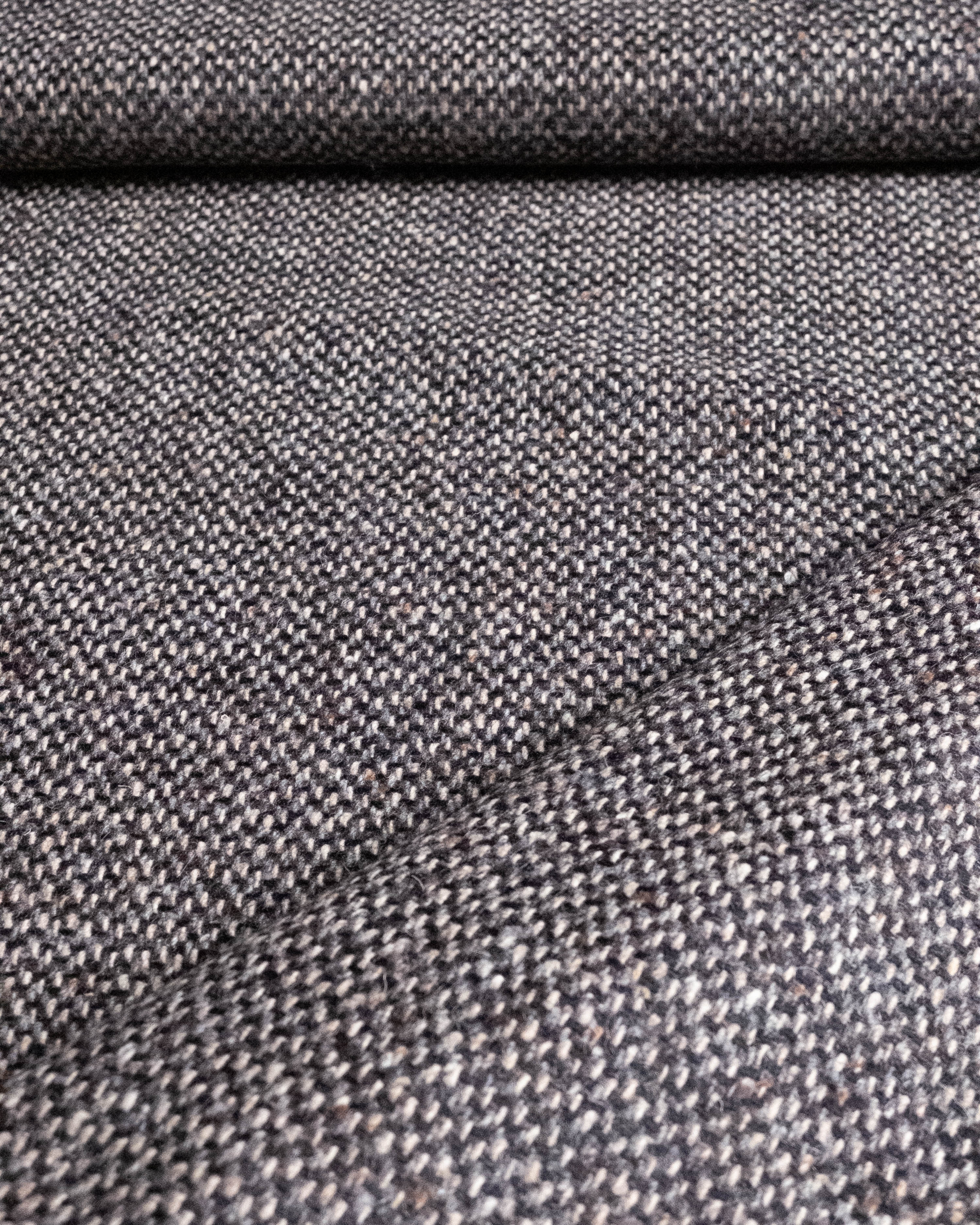A close-up of a woven fabric texture in a heathered gray and white blend, showing the detailed knit pattern and soft folds.